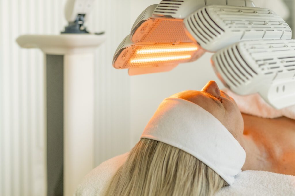 Woman receiving LED light treatment to face